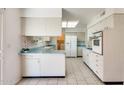 Bright kitchen featuring vintage cabinetry, tile flooring, and modern appliances at 10891 W Clair Dr, Sun City, AZ 85351