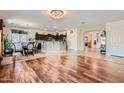 Open-concept living space with hardwood floors, chandelier, and a breakfast bar connecting the kitchen at 13594 W Port Royale Ln, Surprise, AZ 85379