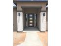 A view of the home's inviting front entrance with stone columns and modern-style door at 17030 W Whispering Rock Trl, Surprise, AZ 85387