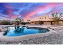 Backyard pool features a unique rock border and mountain views with an elegant stucco house in the background at 19927 W Meadowbrook Ave, Litchfield Park, AZ 85340