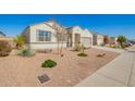 Well-maintained single story home with a two-car garage and desert landscaping, a sidewalk, and street views at 30876 W Verde Ln, Buckeye, AZ 85396