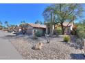 Charming single-story home features desert landscaping, mature trees, and a tile roof on a sunny day at 309 E Mountain Sky Ave, Phoenix, AZ 85048