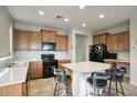 Bright kitchen featuring a center island with bar seating, modern black appliances, and tile flooring at 6109 S 30Th Dr, Phoenix, AZ 85041