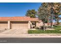 Home exterior showcases tan stucco, red-tiled roof, and a tidy front lawn with mature trees at 945 N Pasadena -- # 52, Mesa, AZ 85201