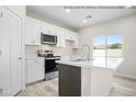 Bright kitchen features white cabinets, quartz counters, stainless appliances and a large center island with a sink at 10947 W Malibu Cir, Arizona City, AZ 85123