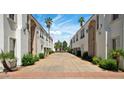 Long driveway between two white buildings with manicured hedges and palm trees leading to an iron gate at 111 W Missouri Ave # E, Phoenix, AZ 85013