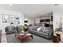 A modern living room featuring grey furniture, a striped rug, and an open floor plan into the kitchen at 11875 E Aster Ln, Florence, AZ 85132