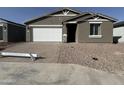 Charming single-story home with a brick driveway and a white garage door at 15752 W Beryl Ave, Waddell, AZ 85355