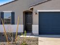 Close up front exterior shot of a gray stucco home featuring a dark blue garage door at 15993 W Cottontail Ln, Surprise, AZ 85387