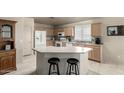 Well-lit kitchen with an island, bar seating, wooden cabinets, and modern white appliances in neutral colors at 16643 N 19Th St, Phoenix, AZ 85022