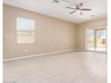 Spacious living room with wood-look floors, ceiling fan, and sliding glass doors to the backyard at 41375 W Barcelona Dr, Maricopa, AZ 85138