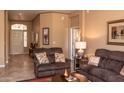 Cozy living room with brown sofas, neutral walls, decorative lighting, and an arched entryway under a neutral light at 5705 S Pinnacle Ln, Gold Canyon, AZ 85118