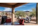 Covered patio with red and grey furniture offering serene views of mountains and desert vegetation under a sunny blue sky at 5705 S Pinnacle Ln, Gold Canyon, AZ 85118