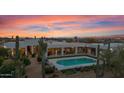 Modern home boasts a private pool, covered patio, and desert landscaping against a beautiful sunset sky at 5914 E Dale Ln, Cave Creek, AZ 85331