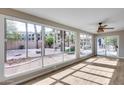 Bright sun room with large windows overlooking the desert landscaped yard, and a ceiling fan at 9513 E Hercules Dr, Sun Lakes, AZ 85248