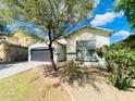 Lovely single-story home with xeriscaping, covered entry, and gray two-car garage at 10030 W Illini St, Tolleson, AZ 85353