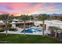 Aerial view of a backyard with a pool, palm trees, and an outdoor kitchen area against a mountain backdrop at 11222 N 73Rd St, Scottsdale, AZ 85260