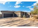 Front exterior with a large three car garage and desert landscaping at 27606 N 61St Pl, Scottsdale, AZ 85266