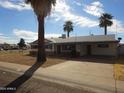 Single-story home with a covered parking area, drought tolerant landscaping and mature palm trees at 3345 W Laurel Ln, Phoenix, AZ 85029