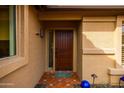 Inviting entryway with a solid wood door, decorative tile, and well-maintained landscaping at 3648 N 162Nd Ave, Goodyear, AZ 85395