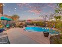 Private backyard oasis with a sparkling pool, string lights, and lush desert landscaping at 3767 W Desert Creek Ln, Phoenix, AZ 85086