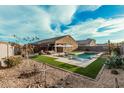 Backyard pool with built-in spa, water feature, artificial turf and lounge seating at 41954 W Plata St, Maricopa, AZ 85138