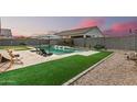 Backyard pool with travertine tile, water feature, artificial turf and lounge seating at 41954 W Plata St, Maricopa, AZ 85138