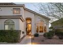 Charming front entrance of the home, showcasing an arched doorway and professionally landscaped yard at 7357 E Rochelle Cir, Mesa, AZ 85207