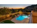 Scenic backyard at sunset featuring a pool, spa, outdoor lighting, and mountain views for a luxurious outdoor experience at 7357 E Rochelle Cir, Mesa, AZ 85207