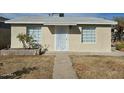 Classic single-story home featuring a walkway leading to an elegant white front door and symmetrical window placements at 9156 W Garfield St, Tolleson, AZ 85353