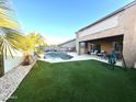 Lush backyard with artificial grass, a sparkling pool, and a covered patio, ideal for outdoor entertaining at 17420 W Mohave St, Goodyear, AZ 85338