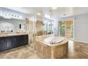 Elegant bathroom featuring a large bathtub, glass-enclosed shower, and vanity with marble countertop at 18256 W Carol Ave, Waddell, AZ 85355