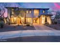 Gorgeous exterior of a home featuring a stone facade, arched entryway, well-manicured landscaping, and beautiful lighting at 28826 N 67Th Dr, Peoria, AZ 85383