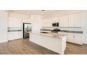 Bright, white kitchen featuring an island with a marble countertop, stainless steel appliances, and wood-look tile floors at 3382 E Saddletree Way, San Tan Valley, AZ 85140