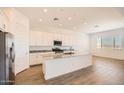 Bright, white kitchen featuring an island with a marble countertop, stainless steel appliances, and wood-look tile floors at 3382 E Saddletree Way, San Tan Valley, AZ 85140