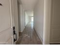Bright hallway with neutral walls and tiled floors leads to open space, creating an inviting atmosphere at 4513 W 95Th Dr, Tolleson, AZ 85353