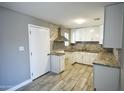 Bright kitchen with stainless steel vent hood, white cabinets, granite countertops, and decorative tile backsplash at 6029 S 6Th Ave, Phoenix, AZ 85041