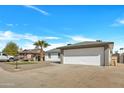 Street view featuring a two-car garage, xeriscaping, and well-maintained lawn at 10013 N 56Th Dr, Glendale, AZ 85302