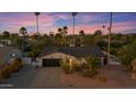 Sunset aerial view of a house with desert landscaping, palm trees, and a two car garage at 5916 E Hearn Rd, Scottsdale, AZ 85254