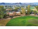 Tile roofed estate on lush green golf course with trees, desert landscaping and mountain views in the background at 7155 E Oakmont Dr, Paradise Valley, AZ 85253