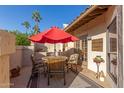 Cozy patio with a vibrant red umbrella, seating area, and view of the desert palms at 9709 E Mountain View Rd # 2703, Scottsdale, AZ 85258