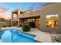 A luxurious backyard pool with a tile border, desert landscaping, a covered patio and a multi-story home at 11082 E Mark Ln, Scottsdale, AZ 85262