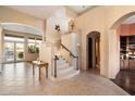 Grand entryway with tile floors, a wooden staircase and trim, neutral-colored walls, and transom windows at 11082 E Mark Ln, Scottsdale, AZ 85262