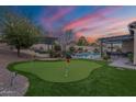 Backyard putting green with flag sticks, bordered by trees, pool, and covered outdoor dining area at 20618 W Western Dr, Buckeye, AZ 85396