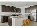 This kitchen showcases a large island with granite countertops, dark cabinetry, and stainless steel appliances at 35250 W Merced St, Maricopa, AZ 85138