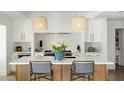 Modern kitchen featuring an island with bar seating, marble backsplash, professional grade stove and white cabinetry at 3640 E Fairmount Ave, Phoenix, AZ 85018