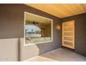 Inviting front porch with wooden door, exterior pot light, wooden plank ceiling, and view into the living room at 849 S Santa Barbara --, Mesa, AZ 85202