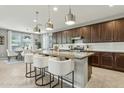 Modern kitchen featuring a large island with seating and pendant lighting, granite counters, and dark wood cabinetry at 8516 W Peppertree Ln, Glendale, AZ 85305