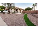 Landscaped front yard featuring desert landscaping, artificial turf, mature trees, and a beautiful tiered fountain at 11197 W Coronado Rd, Avondale, AZ 85392