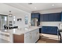Bright kitchen features navy cabinets, stainless steel appliances, quartz countertops, and an island with seating at 23282 S 229Th Pl, Queen Creek, AZ 85142